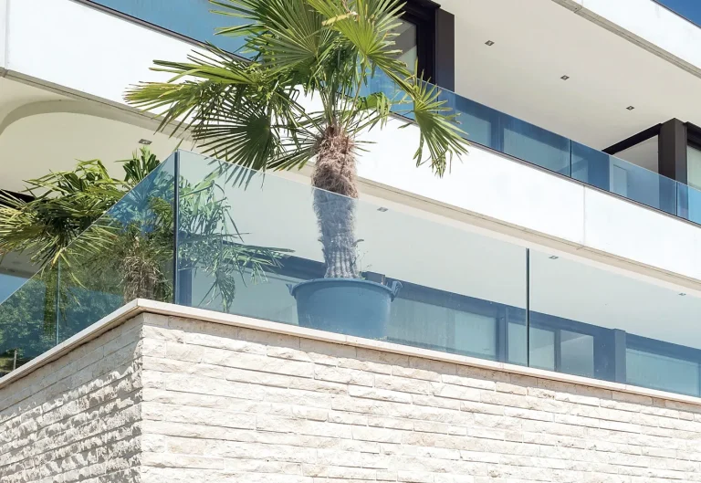 Balkonbrüstung aus Glas an einer Terrasse mit Palme